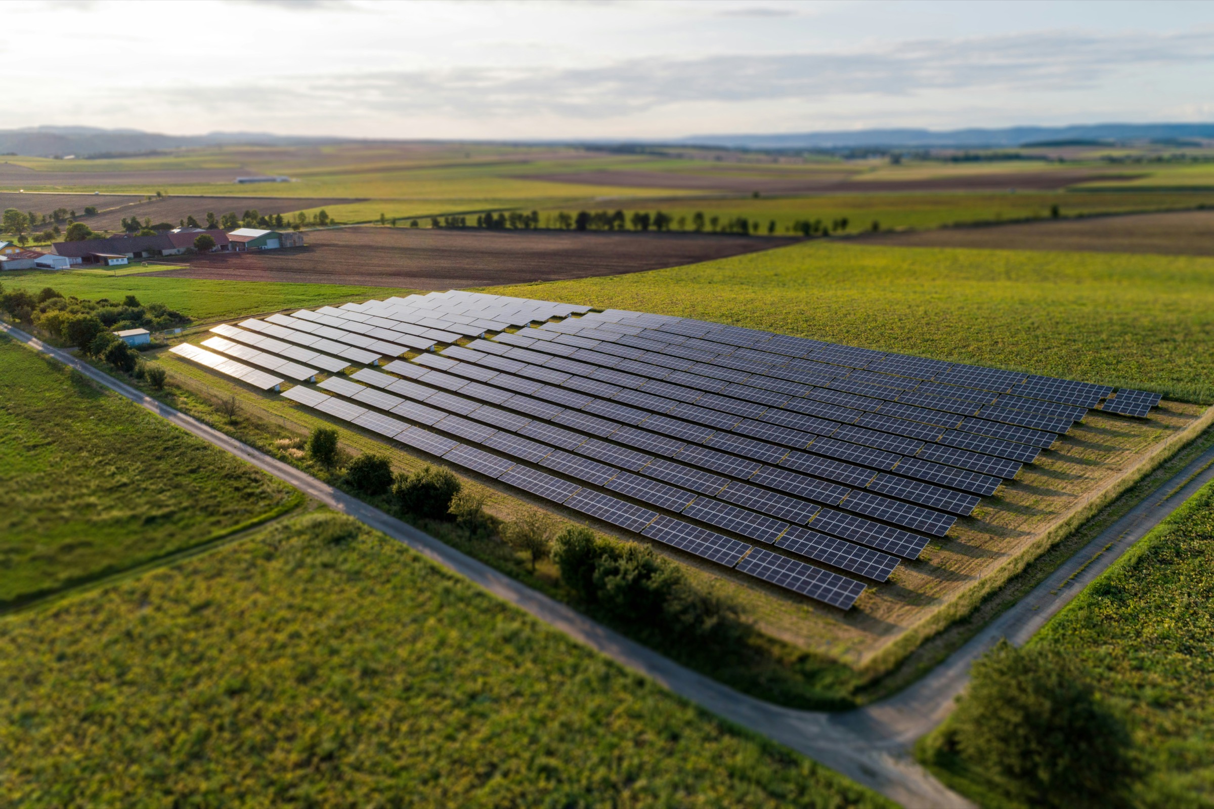 Aerial view of a solar array set among farmland, hedgerows and field boundaries.
