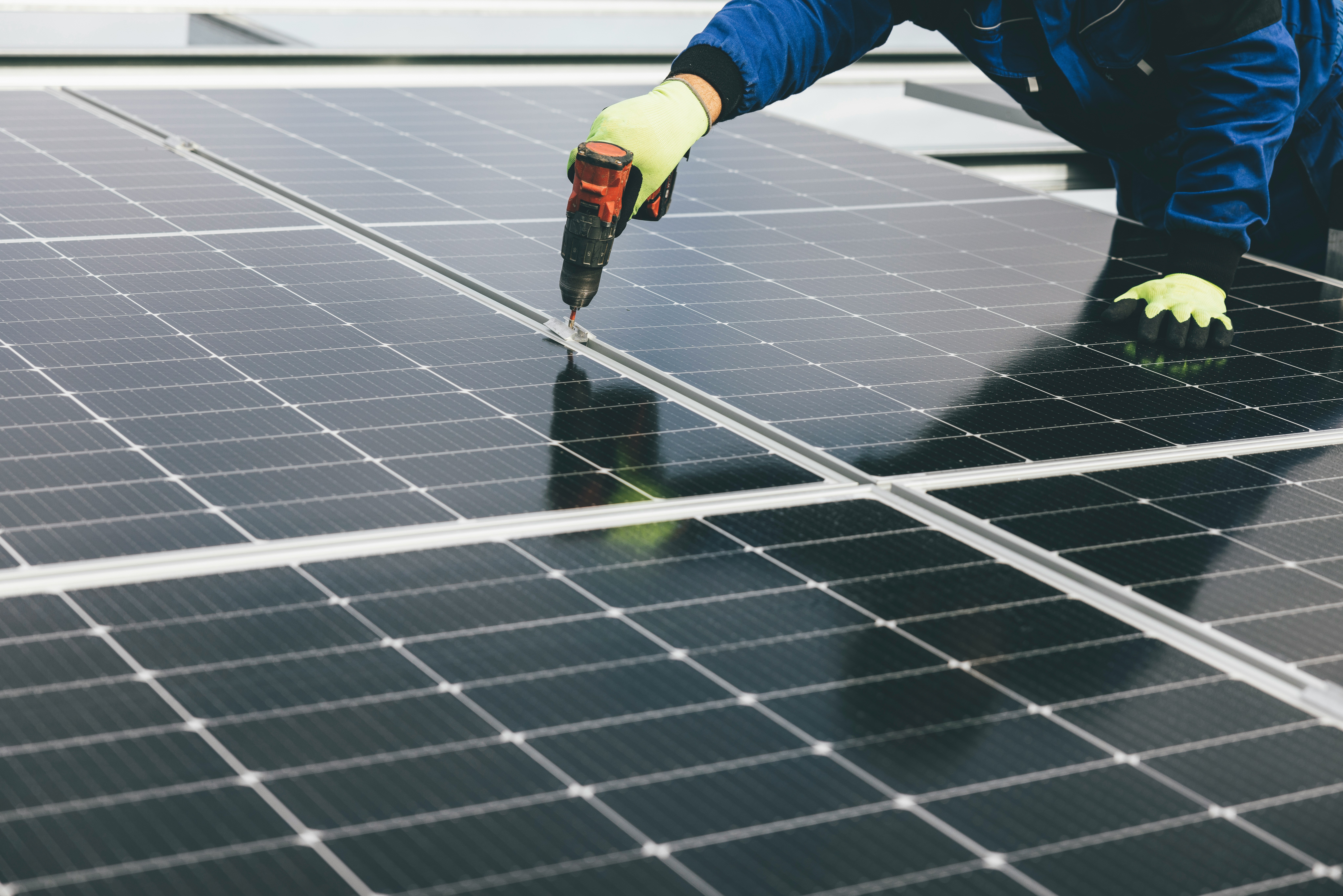 A technician's hands installing a solar panel on site.